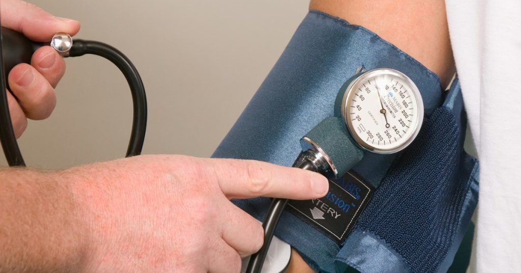 Clinician checking a patient's blood pressure with an arm cuff and gauge